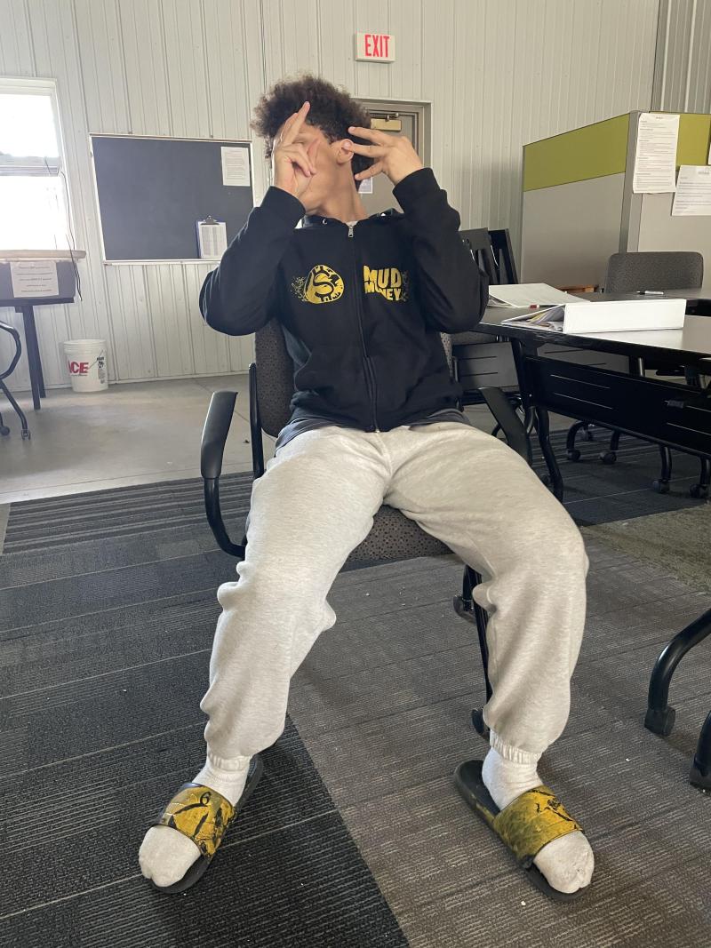 Student posing with their new "Mud Money" personal branded sweatshirt and slides