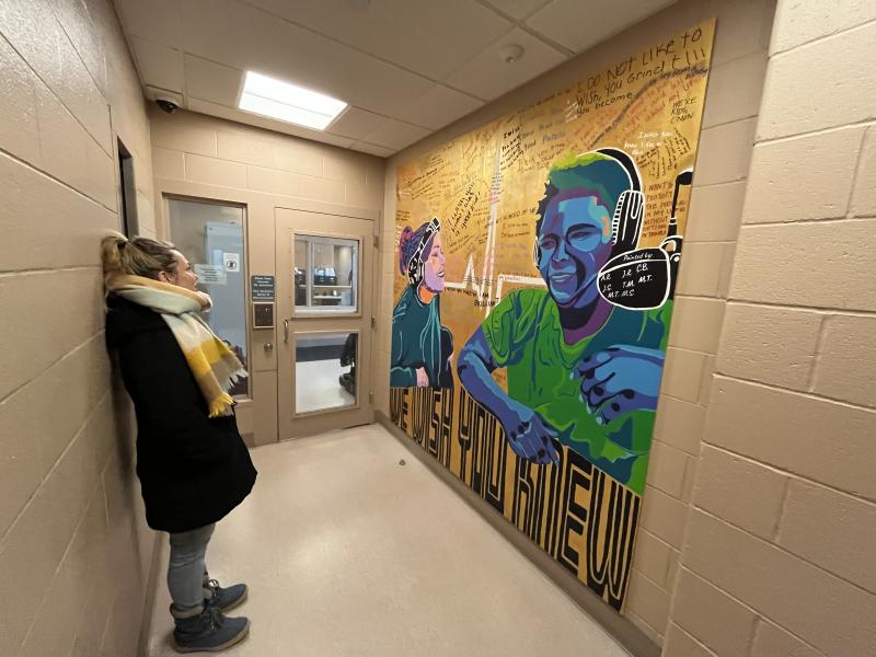 Artist Maria Schirmer standing next to the completed mural at the public entrance to Dane County Juvenile Detention Center